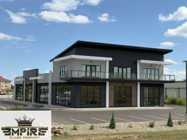 Modern commercial building with large glass windows and balconies under a clear blue sky.