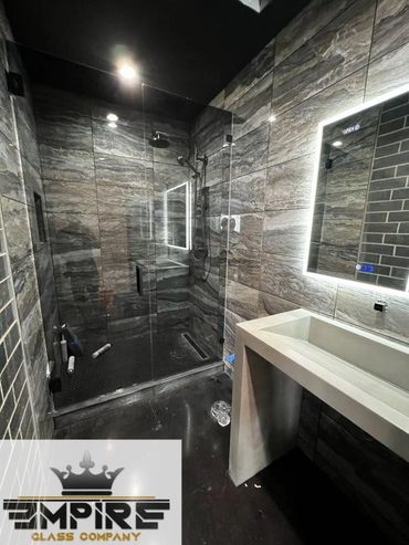 Modern bathroom with glass shower enclosure and illuminated mirror.