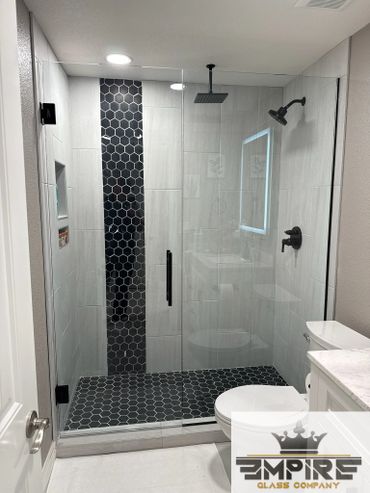 Modern bathroom shower with black hexagonal tiles and glass door.