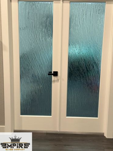 Modern double doors with textured frosted glass panels and a black handle.