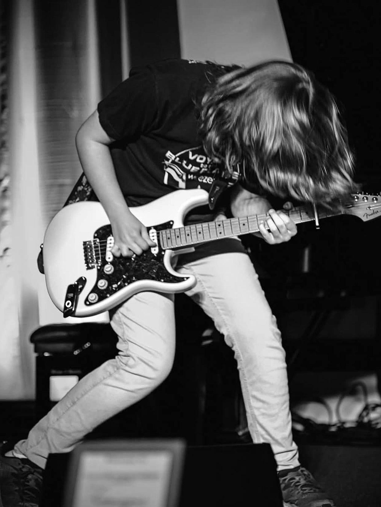 A person playing an electric guitar in front of other people.