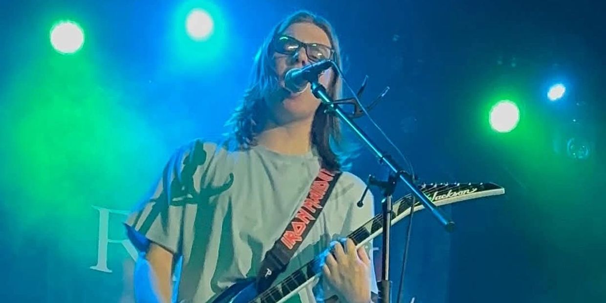 A man with long hair is playing guitar