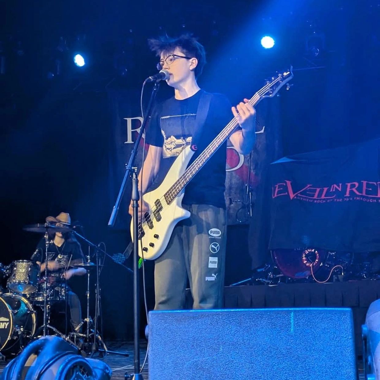 A man holding a guitar on stage with other people.