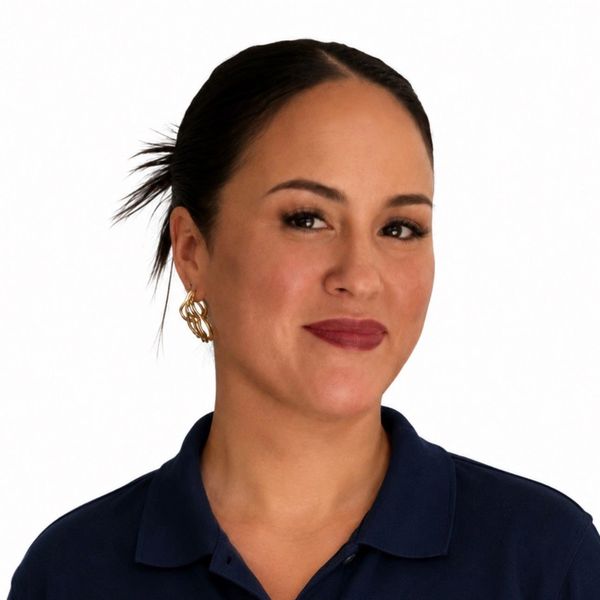 A woman with dark hair in a ponytail wearing gold earrings and a navy blue shirt.