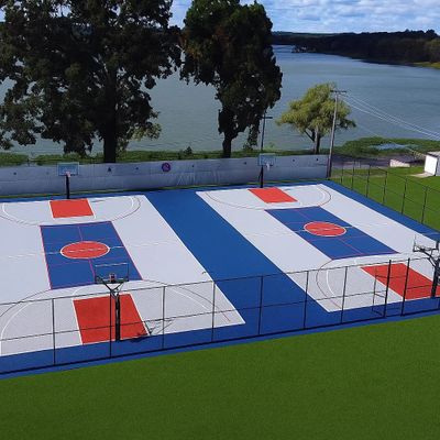 A vibrant outdoor basketball court by a lake with blue and red markings.