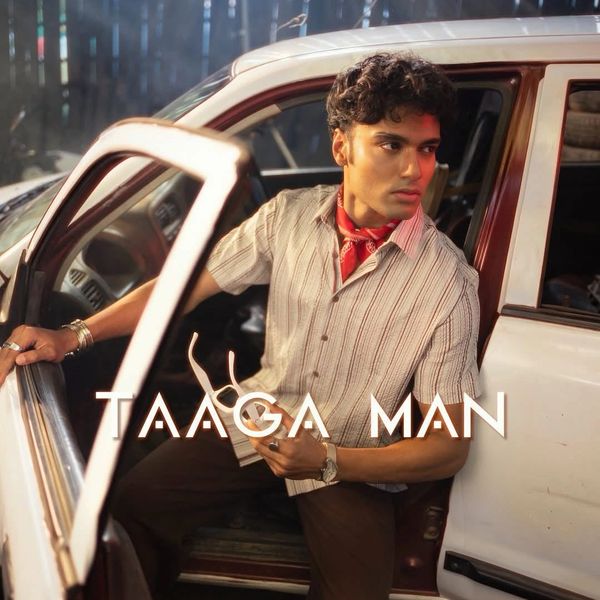 Man sitting in a car with door open, holding sunglasses.