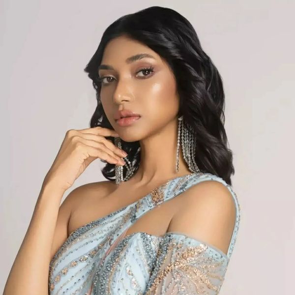 Elegant woman in a beaded blue gown and statement earrings.