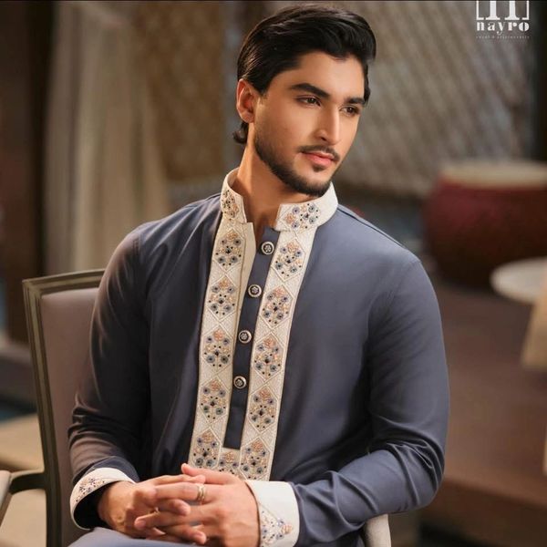 Man in traditional embroidered kurta sitting and posing.