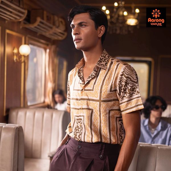 A man in a patterned shirt standing in a vintage setting.