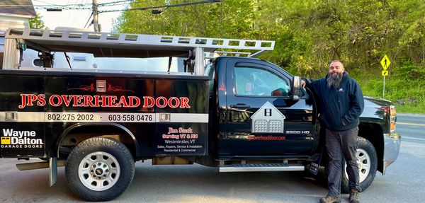 Man standing beside a black JPS Overhead Door service truck.