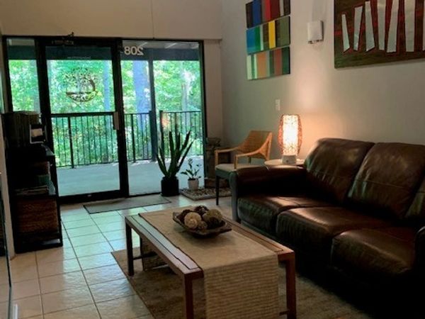 Cozy living room with leather sofa and balcony view of greenery.