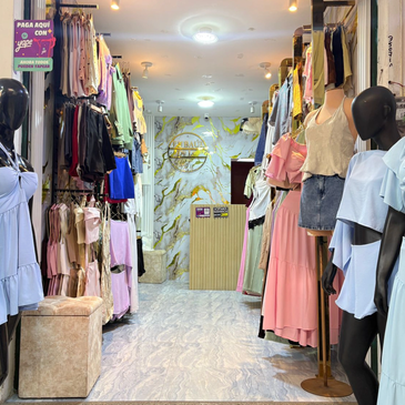 Tienda de ropa con maniquíes y prendas colgadas.