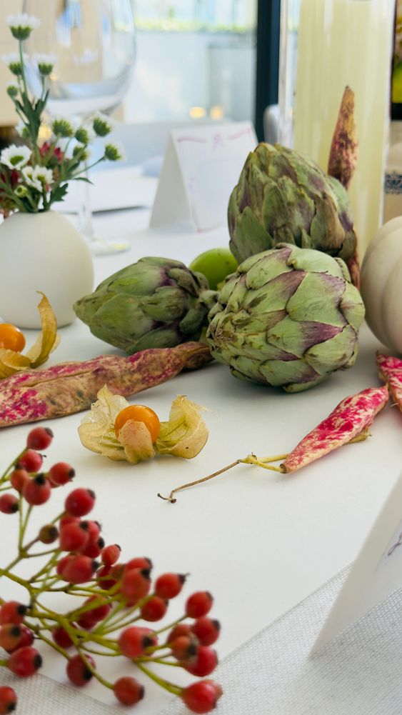 Fresh artichokes and autumn berries on a white tablecloth.