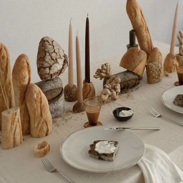Creative bread and candle centerpiece on a dining table with simple place settings.