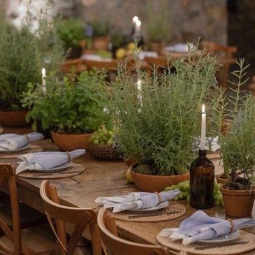 Rustic wooden table with potted herbs and candlelit ambiance.
