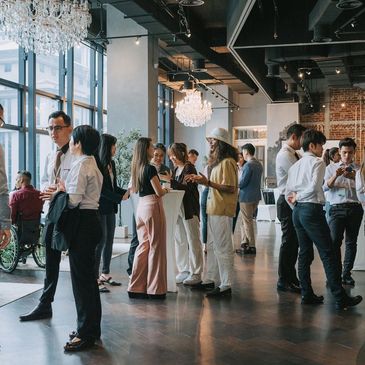 People networking and socializing in a modern, elegant venue with chandeliers.