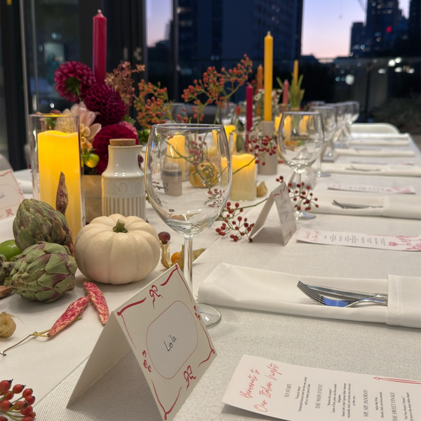 Elegant dinner table setup with candles, flowers, and personalized name cards at dusk.