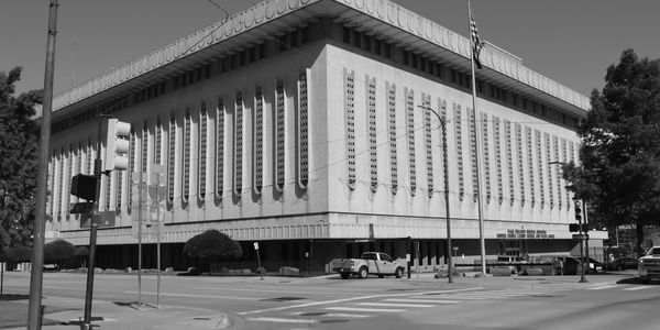 Federal building with unique window design at a street intersection under clear blue sky.