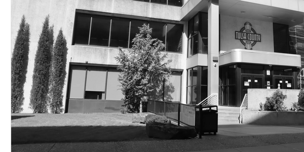 Exterior of Tulsa County building with trees and entrance.