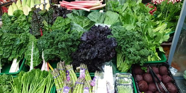 Fresh leafy greens and asparagus displayed at a market stand.