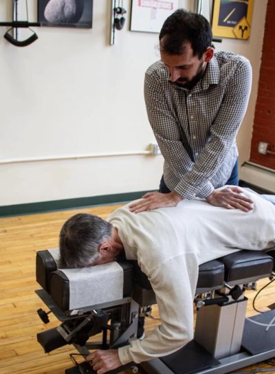 A man receives chiropractic treatment on a specialized table.