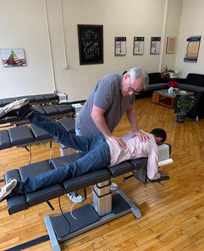 Chiropractor adjusting a patient's back in a clinic room.