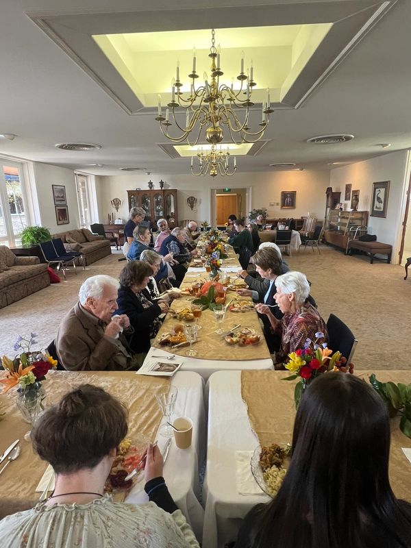 People gathered around a long table enjoying a meal together in a spacious room.