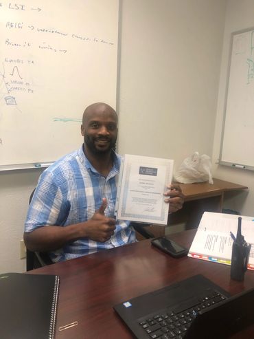 A man holding a certificate sitting at his chair
