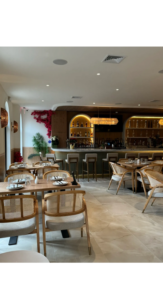 Elegant restaurant interior with wooden furniture and a well-lit bar counter.