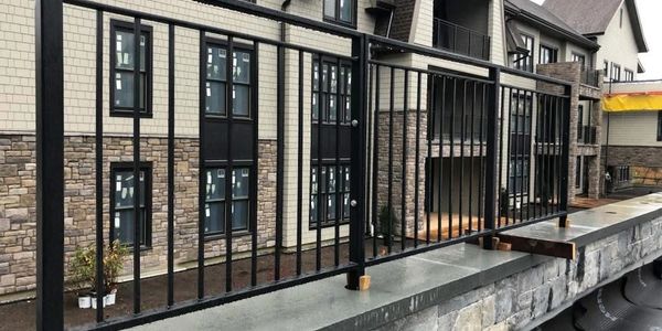 Black metal railing installed on a stone wall outside a building.