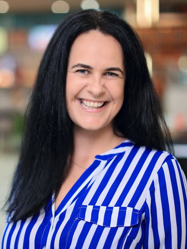Smiling woman with black hair in blue and white striped shirt.