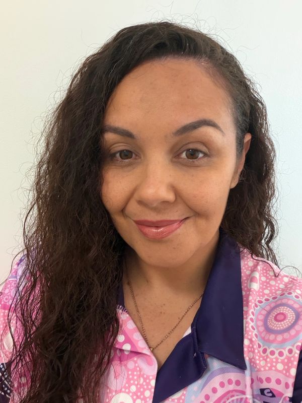 Smiling woman with curly hair in a colorful shirt.
