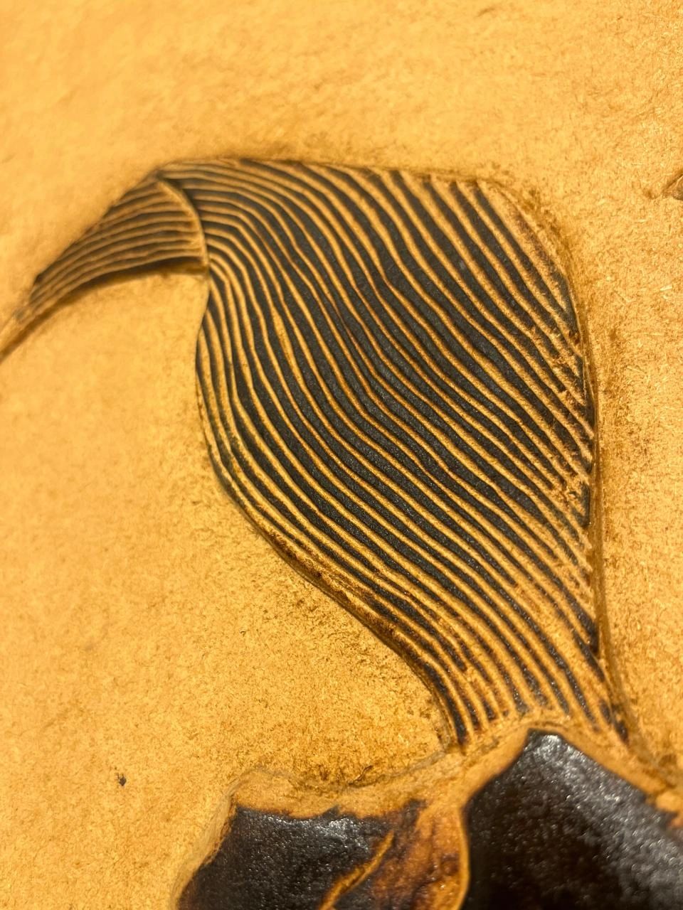 Close-up of a textured, carved leather surface with intricate lines.