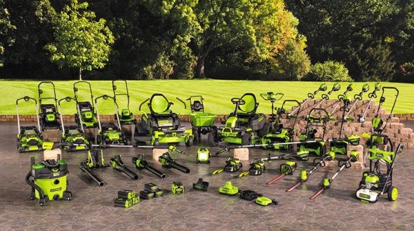 Variety of green and black outdoor power tools displayed on a stone patio.