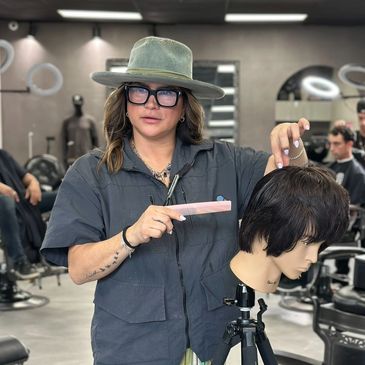 Hair stylist demonstrating haircut techniques on a mannequin head in a salon.