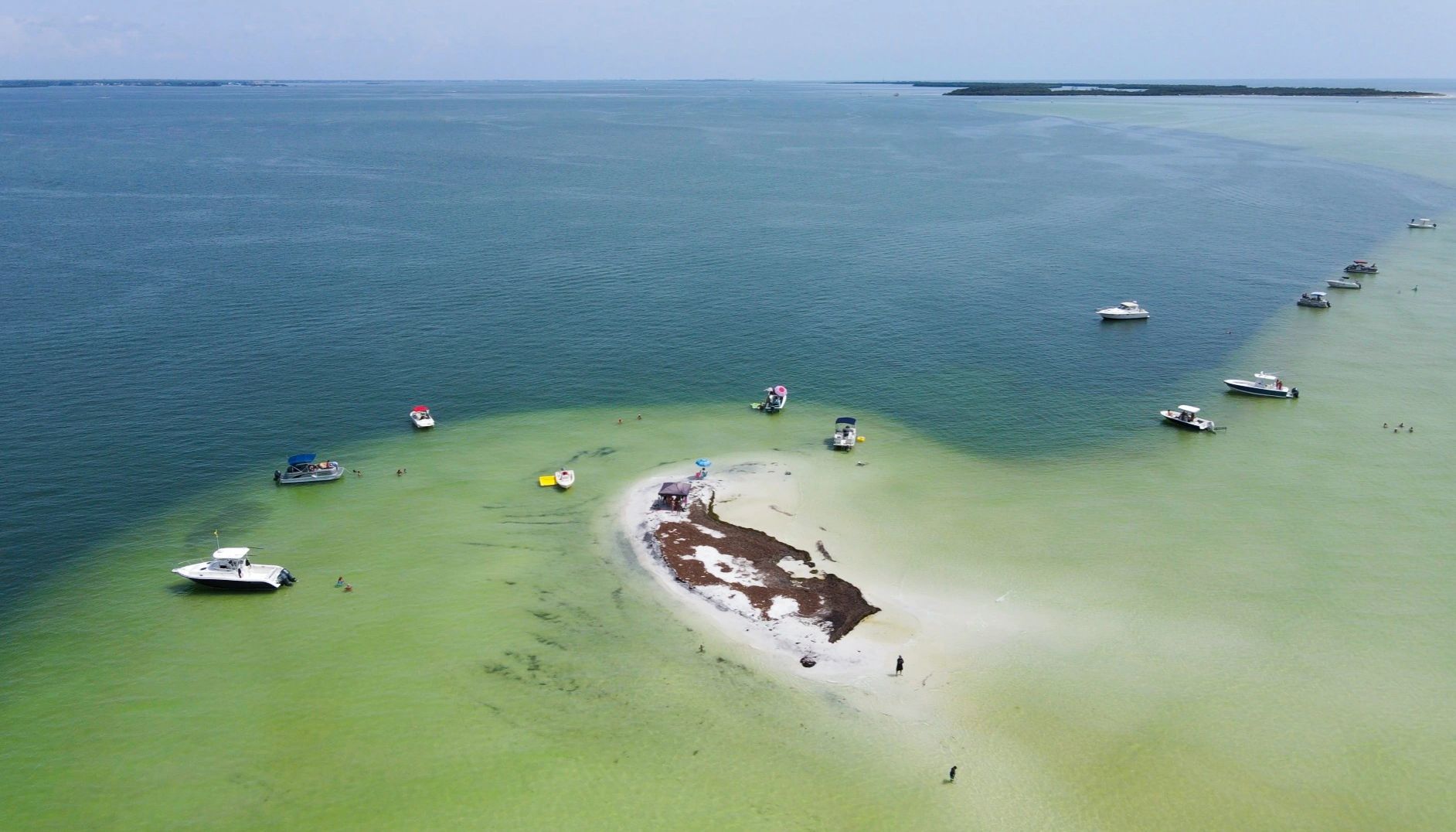 a Florida sandbar with a jet ski driving past & boats anchored around it
