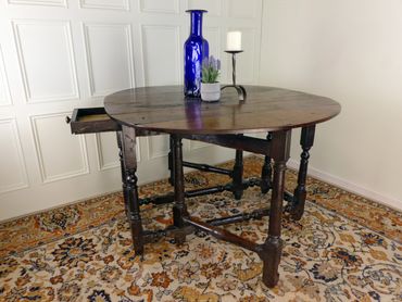 Functional drop leaf mechanism on an antique oak gate-leg table, allowing for versatile table size.