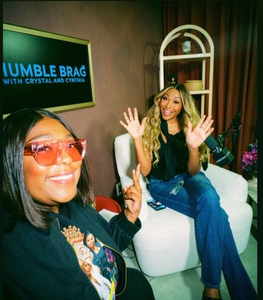 Two women smiling on a podcast set.