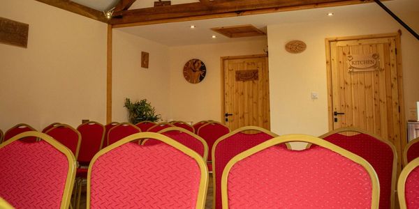 Rows of red chairs in a small room with wooden doors labeled.