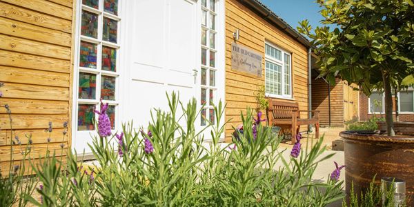 Wooden building with stained glass windows and lavender plants in front.