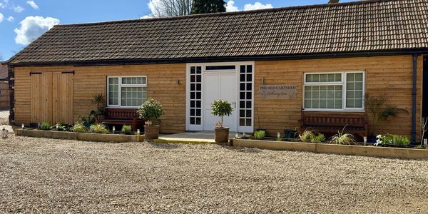 Wooden cottage with benches and plants outside on a sunny day.