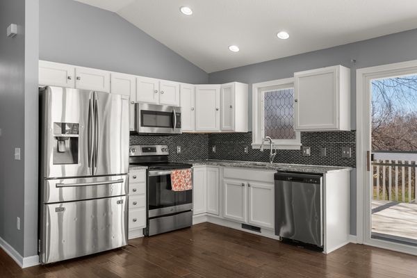 Modern kitchen with stainless steel appliances and white cabinets.
