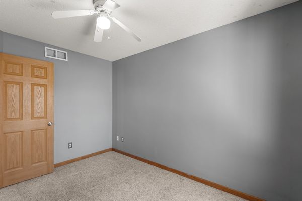 Empty room with gray walls, wood trim, and ceiling fan.