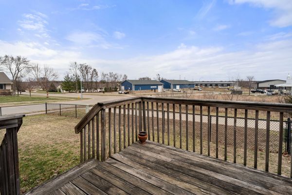 View from a wooden deck overlooking a fenced yard and industrial buildings.