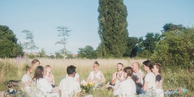 A group enjoying a picnic in a sunny meadow surrounded by nature.