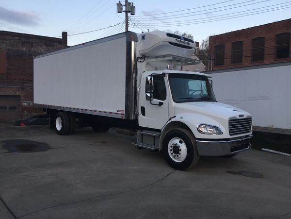 White refrigerator carrier truck parked in an industrial area