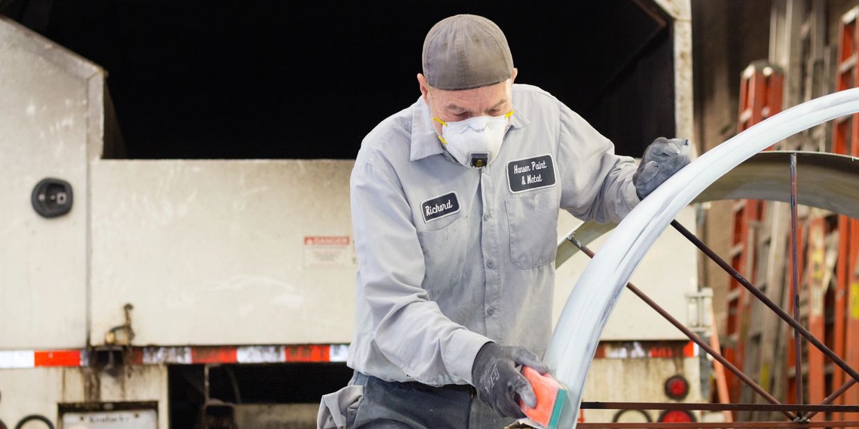 An auto mechanic polishing a car part inside a garage