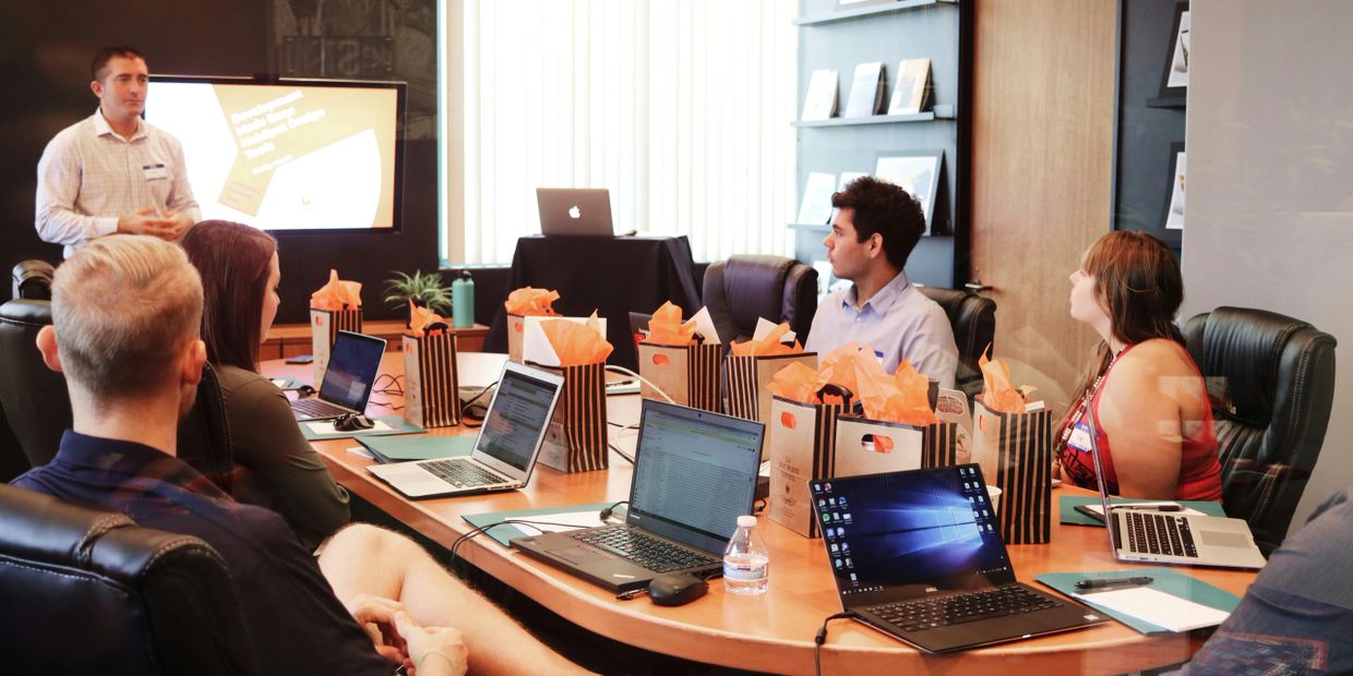 Team attending a presentation in a conference room with laptops and gift bags.