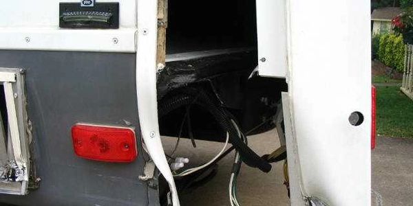Open compartment with exposed wires on a vehicle's side.