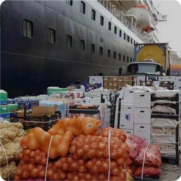 Cargo of vegetables and goods near a ship.